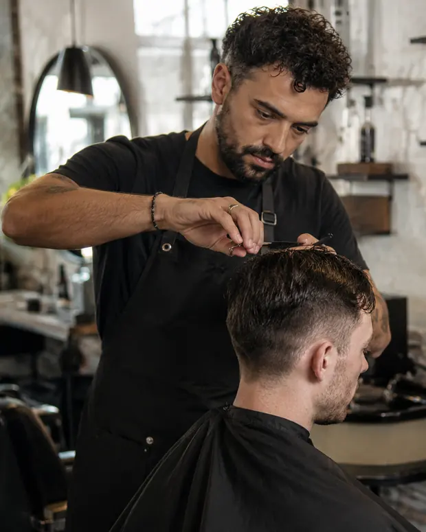 A barber cutting a customer’s hair in the shop.